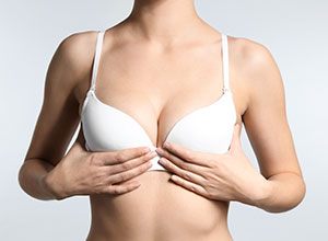 Young woman with beautiful breast on light background