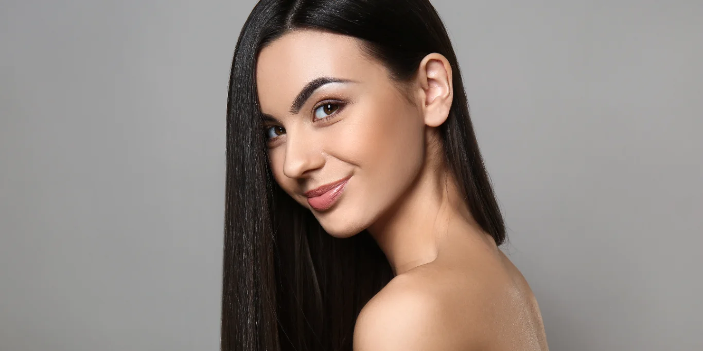 Portrait of beautiful young woman with healthy long hair on grey background